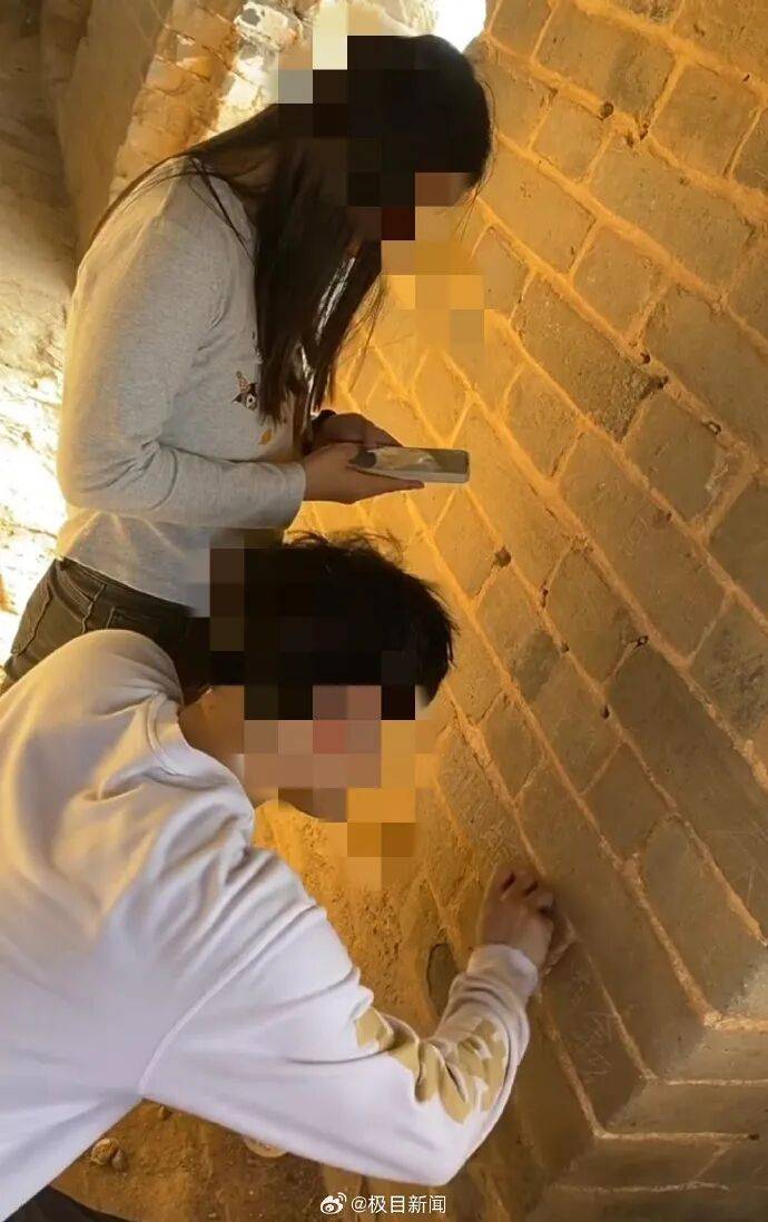 男子在司马台长城墙上刻名字无视劝阻，同行女子拿手机拍照留念